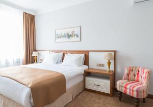 a hotel room with a bed and a chair at Boutique Hotel Kaspi in Temirtaū