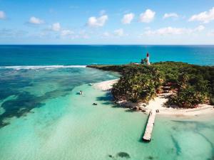 a small island with a lighthouse in the ocean at Appartement vue mer et montagne à 100m de la plage in Le Gosier