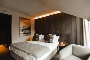 a bedroom with a large bed and a chair at Hotel Sanglier in Durbuy