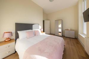 1 dormitorio con 1 cama blanca grande con almohadas rosas en Apartment 1 Isabella House, Aparthotel, By RentMyHouse, en Hereford