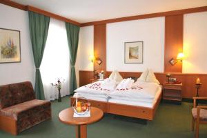 ein Hotelzimmer mit einem Bett, einem Stuhl und einem Tisch in der Unterkunft Hotel Zum Goldenen Hirschen in Freistadt