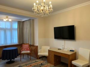 um quarto de hotel com uma televisão, uma secretária e cadeiras em Hotel Neue Post I self check-in em Innsbruck