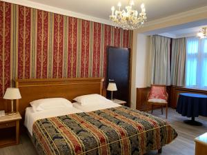 Habitación de hotel con cama y lámpara de araña. en Hotel Neue Post I self check-in en Innsbruck