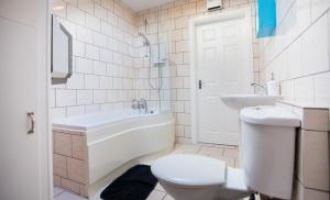 a bathroom with a toilet and a tub and a sink at Albion Guest House & Apartments in Pembroke Dock