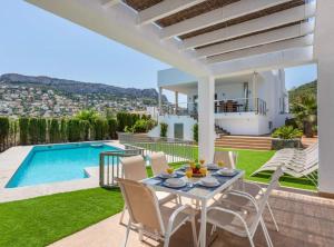 a patio with a table and chairs and a swimming pool at Villa Drago - Plusholidays in Calpe