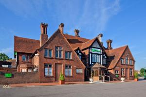 um grande edifício de tijolos castanhos com duas chaminés em Holiday Inn London-Bexley, an IHG Hotel em Bexley