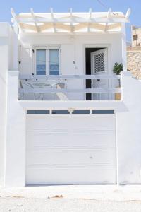 a white house with a white garage door at Ostraco Syros in Vari