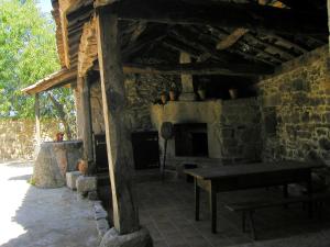 a stone house with a table and a fireplace at Casa de Campos in Silleda