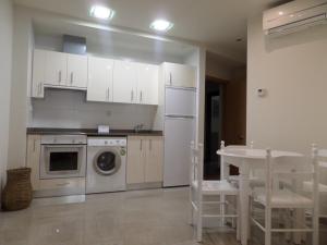 a kitchen with white cabinets and a table and a dishwasher at El Lagar De ElCiego in Elciego