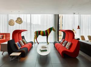 uma sala de estar com duas cadeiras vermelhas e uma estátua de cavalo em citizenM Glasgow em Glasgow