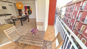 een houten tafel met een vaas met bloemen op een balkon bij Luxury City Center Apartment by NRAS in Alicante +30 foto's
