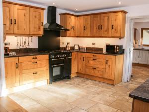 a kitchen with wooden cabinets and a black stove top oven at Dingle Cottage in Shrewsbury