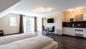 a bedroom with a bed and a kitchen with a table at Gästehaus Lemerhof in Oberding