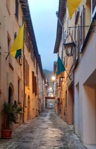 un callejón con banderas al lado de los edificios en Hotel Ristorante Cibarium, en Gualdo Tadino