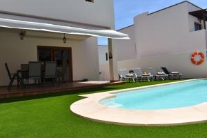 un patio trasero con piscina y césped verde en CASA BOUTIQUE LANZAROTE, en Costa Teguise