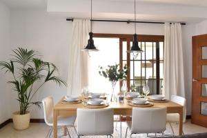 a dining room with a wooden table and white chairs at CASA BOUTIQUE LANZAROTE in Costa Teguise
