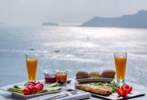 a table topped with plates of food and drinks at Nostos Apartments in Oia