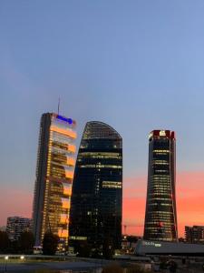 three tall buildings in a city at sunset at On the top floor watching CityLife and MiCo in Milan