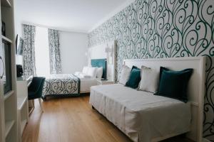 a bedroom with two beds and a wall with a wallpaper at Hotel Città di Parenzo in Trieste