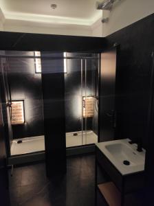 a black bathroom with a shower and a sink at Greg&Tom Hostel in Krakow