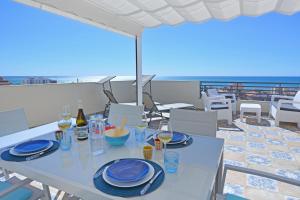 a table with blue plates and wine glasses on a balcony at Penthouse with Panoramic View by NRAS in Santa Pola