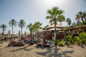 a beach with people sitting on chairs and umbrellas at Luxurious beachside in the heart of Puente Romano in Marbella