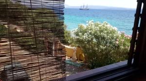 a view of the ocean from a window with blinds at Appartamenti al mare in SantʼAntìoco