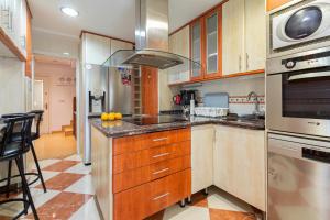 a kitchen with wooden cabinets and stainless steel appliances at Paraiso Rooms Coliving in Madrid