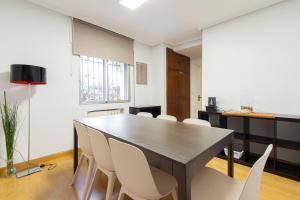 a dining room with a table and white chairs at Paraiso Rooms Coliving in Madrid