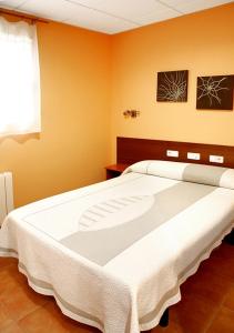 uma grande cama branca num quarto com paredes cor-de-laranja em Alojamiento Numancia Pensión em Burgos