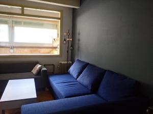 - un salon avec un canapé bleu et une fenêtre dans l'établissement Apartamento en la Molina, à La Molina