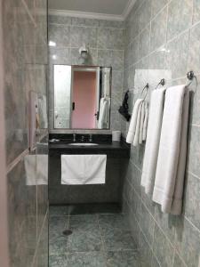a bathroom with a sink and a mirror and towels at Pousada Ararinha Azul in Campos do Jordão