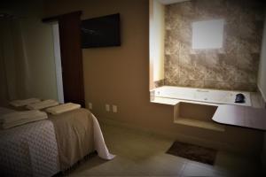 baño con cama, lavabo y ventana en Terra D` Ouro Apart Hotel, en São João del Rei