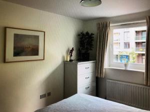 a bedroom with a bed and a dresser and a window at Kingston Flat in Kingston upon Thames