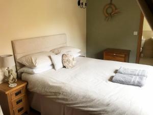 a bedroom with a large white bed with two pillows at Oak Barn in Wigginton