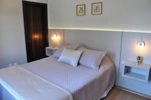 1 dormitorio con 1 cama blanca y 2 almohadas en Apartamento Florido Centro Gramado, en Gramado
