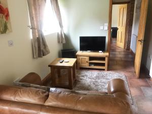 un soggiorno con divano e TV di Oak Barn a Wigginton
