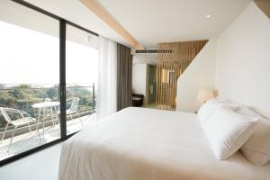 a bedroom with a white bed and a large window at Centara Q Resort Rayong in Mae Pim