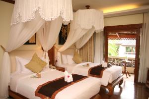 a bedroom with two beds with curtains and a window at Khum Phaya Resort & Spa Boutique Collection in Chiang Mai