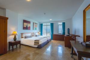 a hotel room with a bed and a desk and a desk at Waterfront Suites Phuket by Centara in Karon Beach