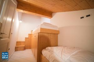 una piccola camera con letto e soffitto in legno di Trentino Apartments - Casa Moser a Folgaria