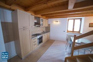 a kitchen with white cabinets and a table and a dining room at Trentino Apartments - Casa Moser in Folgaria