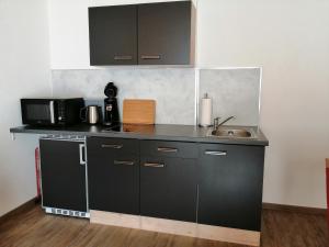 uma cozinha com armários pretos e um lavatório em Landhotel Reckenberg em Stegen