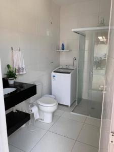 a white bathroom with a toilet and a sink at Casa com piscina in Porto Belo