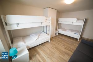 Trentino Apartments - Casa Marzari في فولاريا: سريرين بطابقين في غرفة صغيرة مع أرضيات خشبية