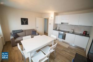 a kitchen and living room with a white table and chairs at Trentino Apartments - Casa Marzari in Folgaria