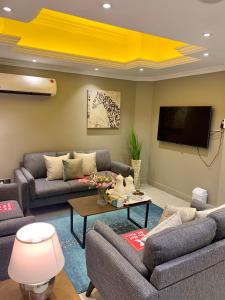 a living room with couches and a flat screen tv at Al Rawdha Hotel Apartments in Sharjah