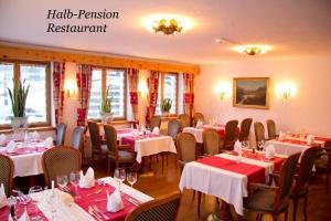 a restaurant with tables and chairs with red tablecloths at Hotel Nolda in St. Moritz