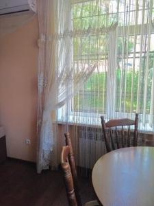 een tafel en stoelen voor een raam bij Apartments comfortablе in Tsjernivsi