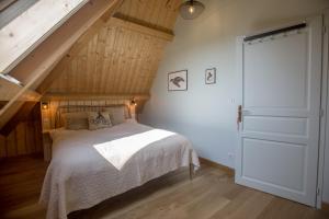 a bedroom with a bed with white sheets and an attic at Domaine de la Valaine in Étretat
